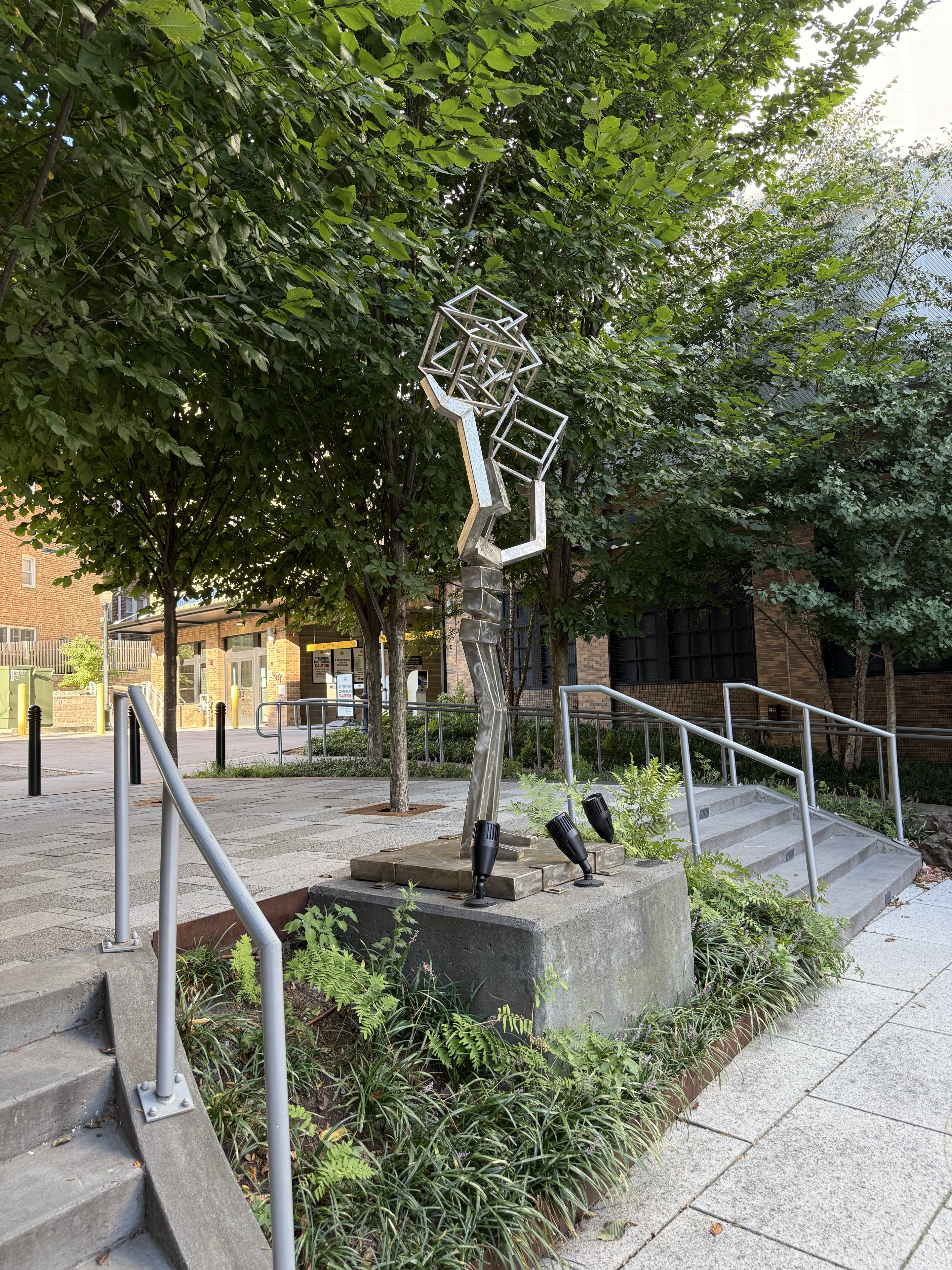 A geometric sculpture beside the plaza steps and railings.