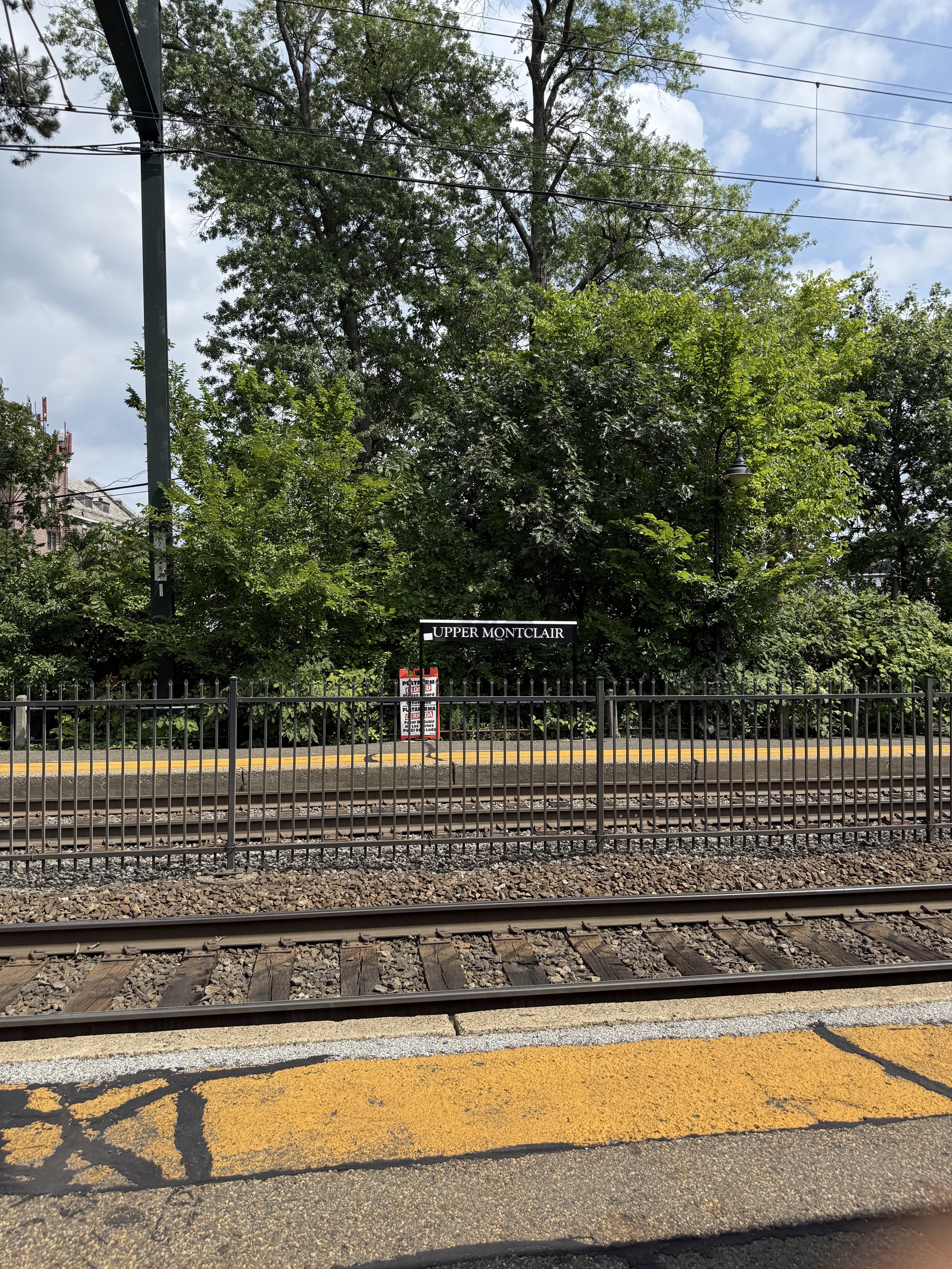 Upper Montclair station sign and railway tracks, viewed from the opposite platform.